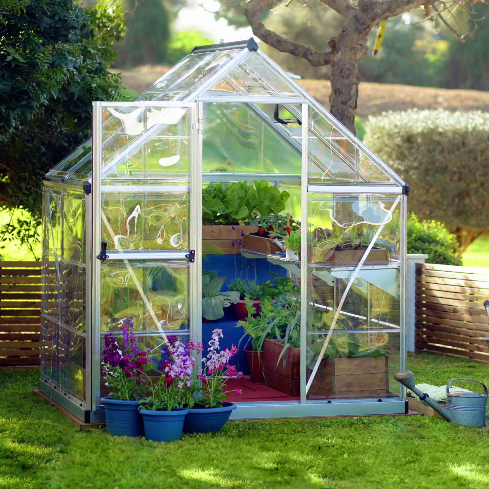 A greenhouse made from clear windows with silver metal framing